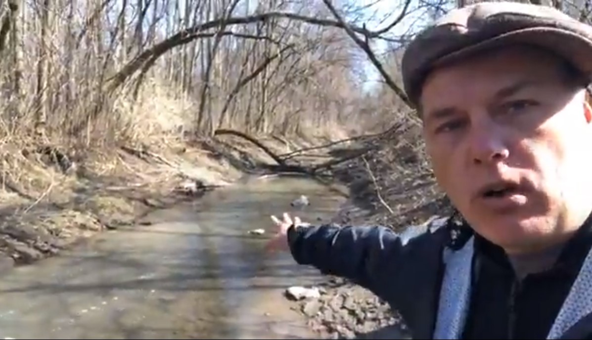 De l’eau blanchâtre du dépôt à neiges coule dans le Boisé Du Tremblay